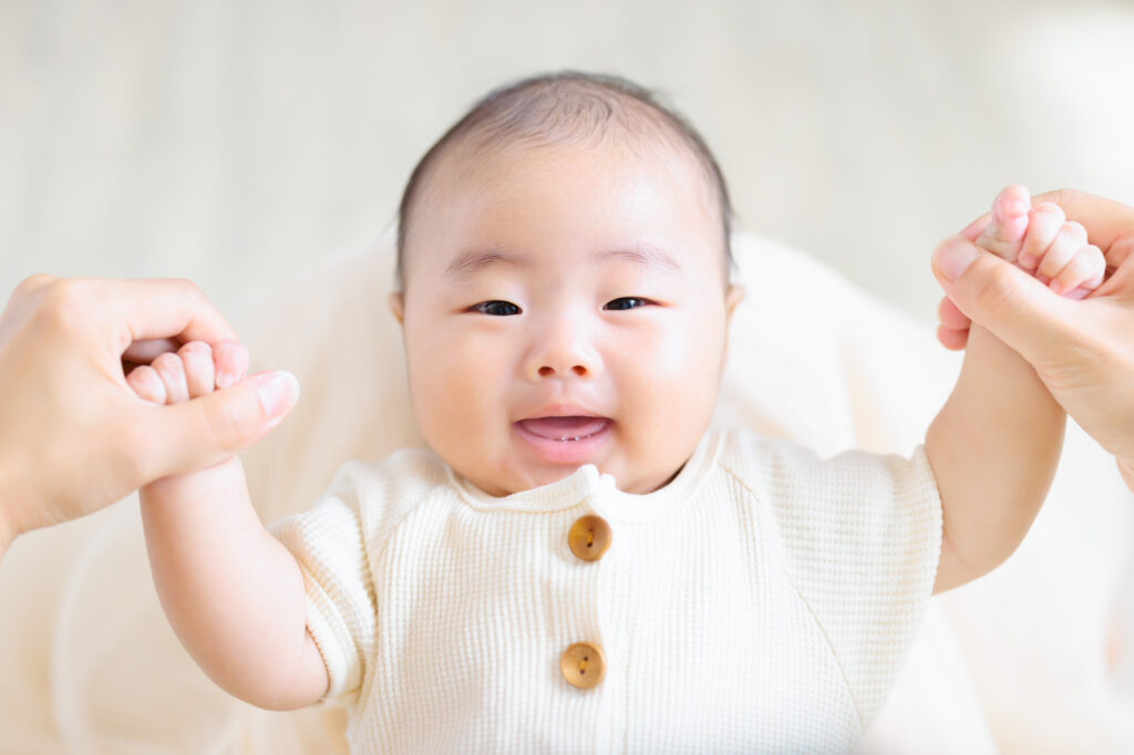 手をつないで笑顔の乳児